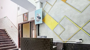 A reception area with a marble staircase, a reception desk, and a geometric wall design. - Townhouse Prakash Continental (New Delhi)