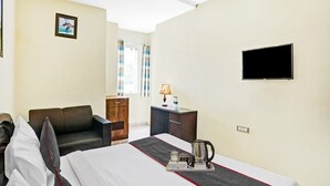 A hotel room with a bed, a desk, a chair, a TV, and a window with curtains. - Townhouse Prakash Continental (New Delhi)