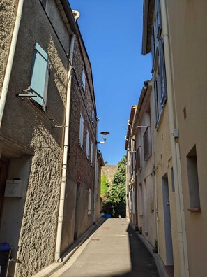 A narrow street with buildings on either side, featuring a mix of brick and plaster facades, and a clear blue sky above. - Quiet village house in Alénya—5 km from the beaches (Alénya)