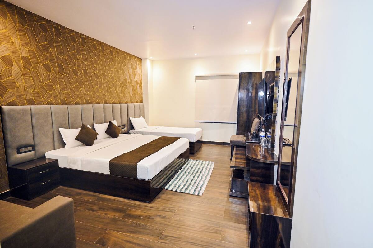 Een moderne hotelkamer met een groot bed, een losse zithoek, een bureau met spiegel en een groot raam.