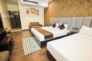 Habitación de hotel con una cama grande, un sofá, un tapete estampado y una pared con diseño geométrico.