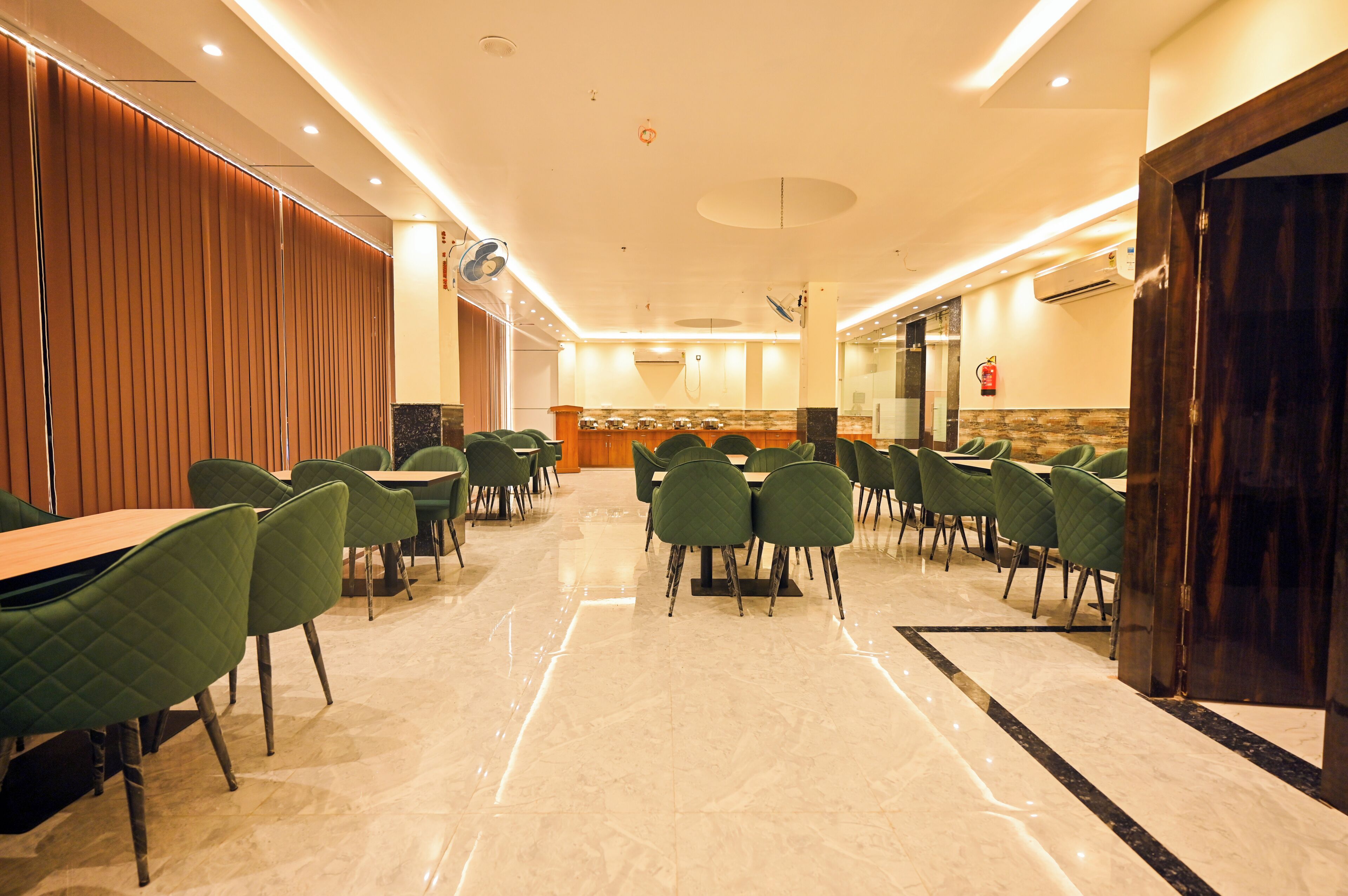 A spacious indoor area with multiple tables and chairs, a polished marble floor, and a wooden partition on one side.