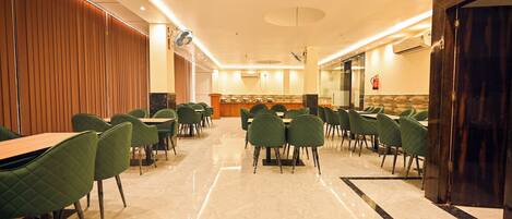 A spacious indoor area with multiple tables and chairs, a polished marble floor, and a wooden partition on one side.