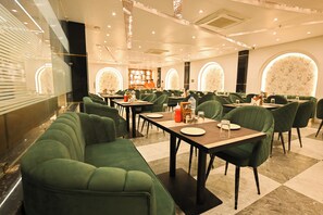 Un ristorante con sedute rivestite in verde, pavimento in marmo e un design d'interni moderno.