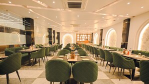 Un vaste espace dédié à la salle à manger, avec de nombreuses tables et chaises, un bar central et un aménagement intérieur moderne.