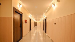 Un long couloir bien éclairé, avec des portes en bois et un plancher ciré.