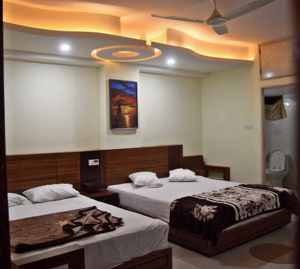 A hotel room with two beds, a ceiling fan, a painting, and a shower area.