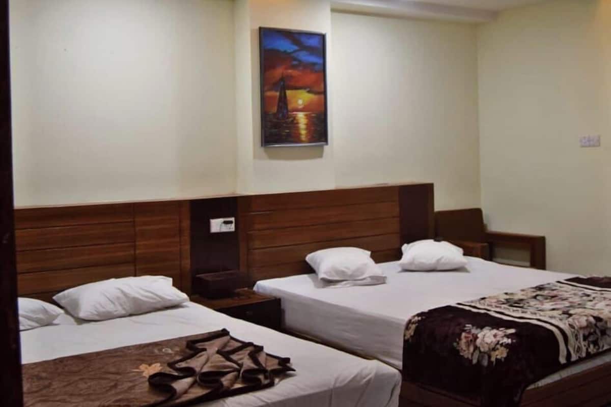 Ein Hotelzimmer mit zwei Betten, einem Bild an der Wand und einem Deckenventilator.