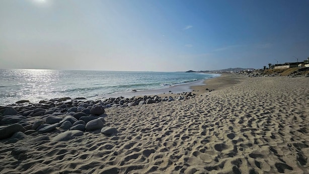 A beach with a rocky shoreline and a clear sky.