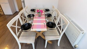 A dining table with four chairs, a pink and white striped tablecloth, and a vase with pink flowers. - Charming 5-Bedroom Townhouse in Central Gloucester (Gloucester)