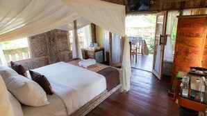A room with a bed, a television, and a table with items on it. - Deluxe room with pool view at Ubud (Bali city)