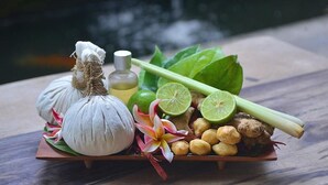 A tray with garlic, lemongrass, ginger, lime, and a bottle of oil on a wooden table. - Deluxe room with pool view at Ubud (Bali city)