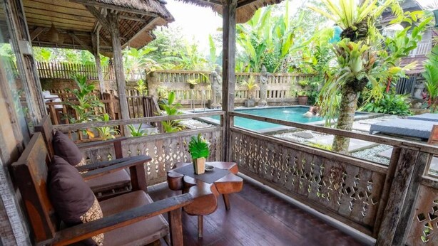 A wooden deck with a pool, surrounded by lush greenery and tropical plants. - Deluxe room with pool view at Ubud (Bali city)