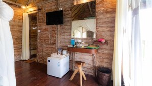 A rustic room with wooden walls, a flat-screen TV, a small sink, and a refrigerator. - Charming Deluxe room Upper floor at Ubud (Ubud)