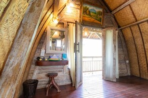 Un dormitorio rústico en el ático con techo de madera, un banco de madera, una mesita con espejo y vistas al exterior.