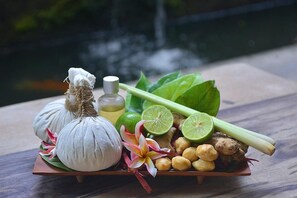 Una bandeja con ajo, hierba limón, jengibre, lima y una botella de aceite sobre una superficie de madera.