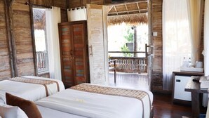 Una habitación con dos camas, un armario de madera, un escritorio pequeño y un balcón con barandilla.