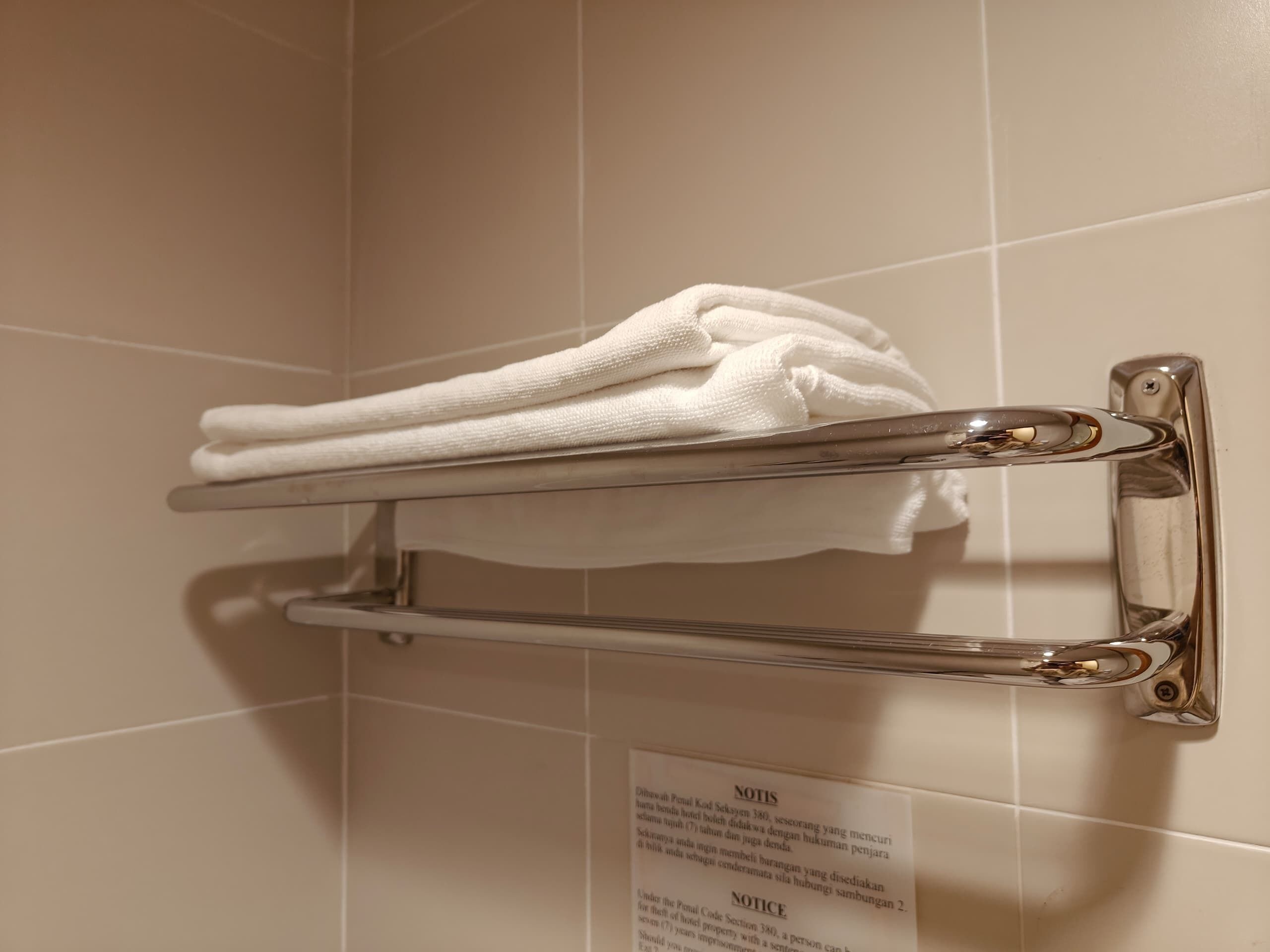 A towel rack with folded towels against a tiled wall.