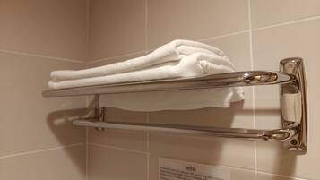 A towel rack with folded towels against a tiled wall.