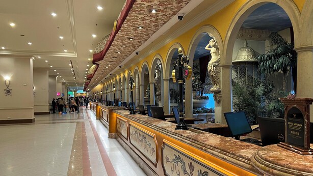 Un hall d’hôtel doté d’un long comptoir d’accueil, de plusieurs arcades et d’un plafond décoratif.