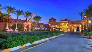 A hotel entrance with a well-lit facade, palm trees, and a giraffe statue. - Spacious Resort Beach Villa with Private Pool Nabq (South Sinai Governorate)