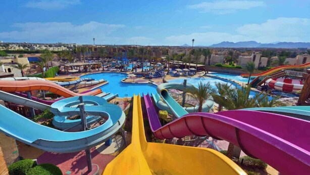 A water park with multiple slides and pools, surrounded by palm trees and a mountainous backdrop. - Spacious Resort Beach Villa with Private Pool Nabq (South Sinai Governorate)