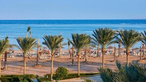 A beachside resort with palm trees, sun loungers, and a view of the ocean. - Spacious Resort Beach Villa with Private Pool Nabq (South Sinai Governorate)