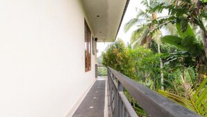 A narrow corridor with a metal railing, surrounded by lush greenery and palm trees. - Deluxe room upper floor with pool & nature view (Bali)
