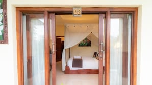 A room with a bed, a window, and a door with the number 02. - Deluxe room upper floor with pool & nature view (Bali)