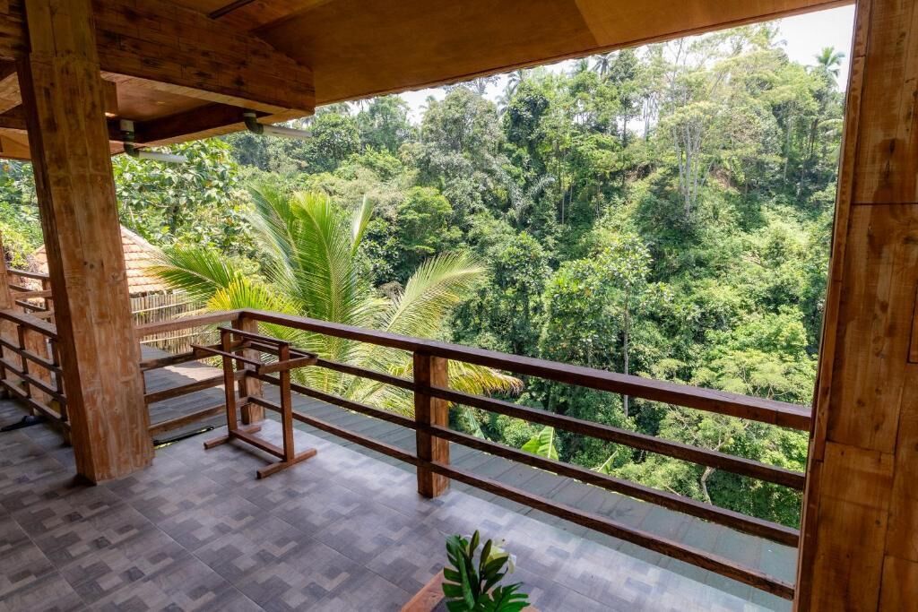 Un balcone in legno con vista su una fitta foresta tropicale.
