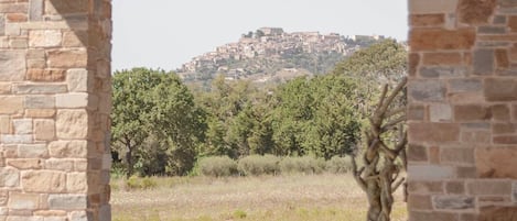 An arched stone structure with a view of a hilltop settlement.