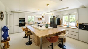 Een moderne keuken met witte kasten, een houten eiland en barstoelen.