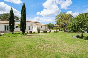 A house with a tiled roof, a well-maintained lawn, and several trees. - Luxury villa, gated community in Domène (Grimaud)
