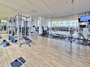 Ein modernes Fitnessstudio mit verschiedenen Gewichtstrainingsgeräten, großen Fenstern und einer geräumigen Gestaltung.