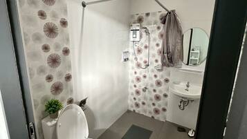 Een moderne badkamer met toilet, douche en wastafel.