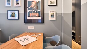 Een moderne kamer met een houten tafel, een ingelijste poster en een grijze muur met ingelijste foto's.