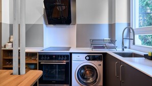 Een moderne keuken met een inbouwoven, een wasmachine en een koffiezetapparaat.