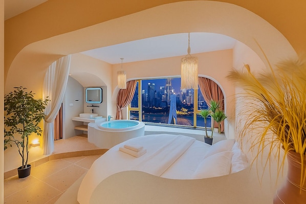 Une chambre moderne avec un grand lit, une baignoire, une coiffeuse et une vue sur la ville.
