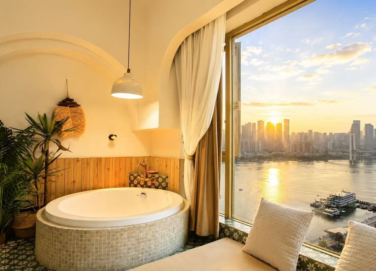 A room with a large bathtub, a view of a city skyline, and a river.