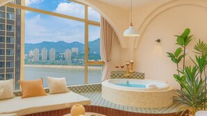 Ein Zimmer mit großem Fenster, einer Badewanne, einem Sofa und einer Pflanze.
