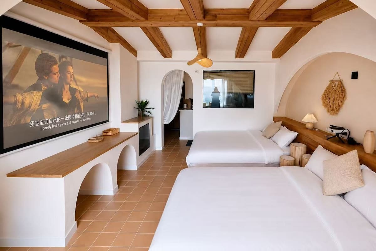 Une chambre avec deux lits, une télévision, un bureau et une vue sur un immeuble.