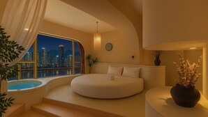Ein modernes Schlafzimmer mit einem gebogenen Bett, Blick auf die Stadt, einem kleinen Pool und einer Treppe zu einem Außenbereich.