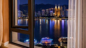 Überblicksaufnahme einer beleuchteten Stadtlandschaft bei Nacht, mit Gebäuden und einem Fluss.