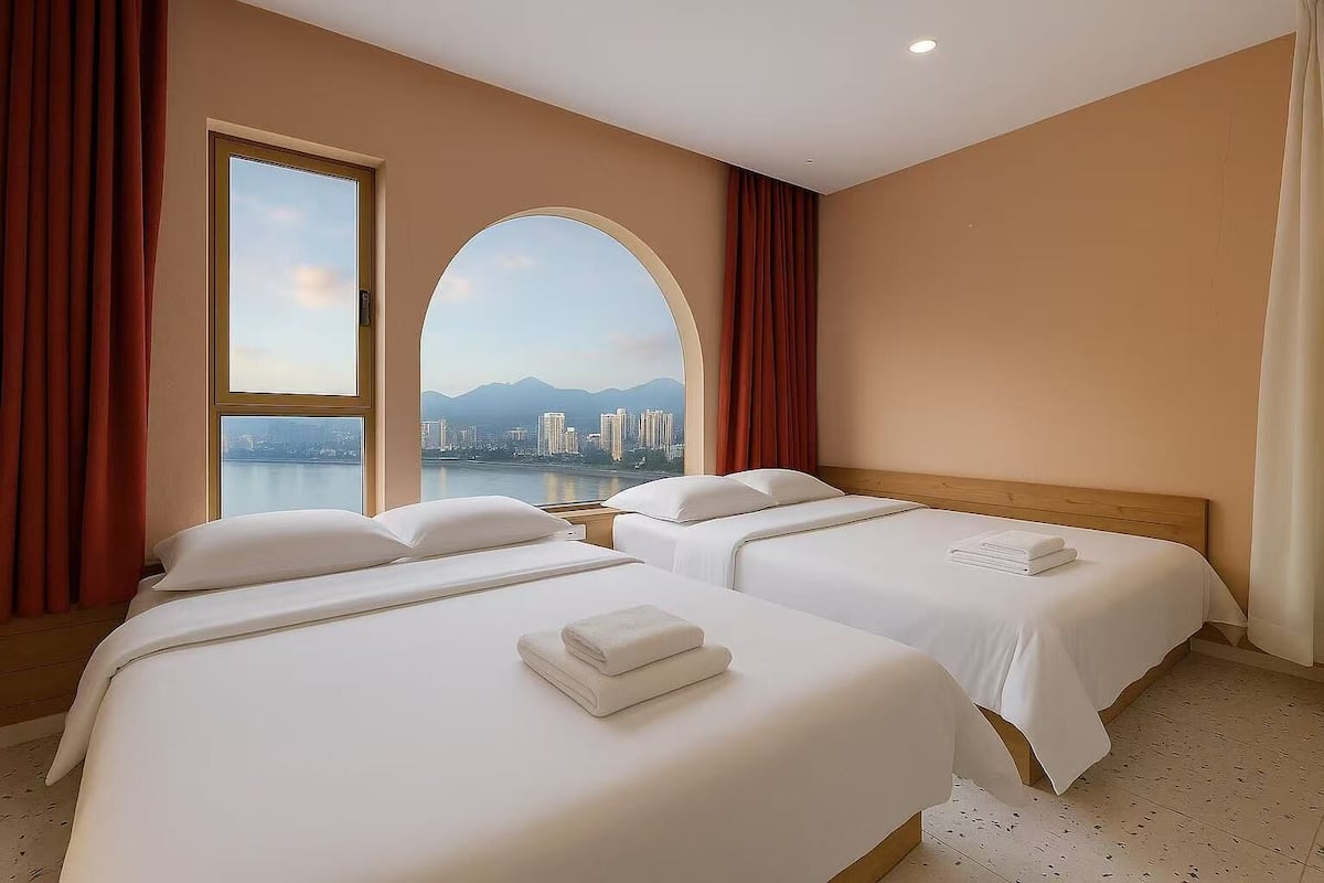 Ein Hotelzimmer mit zwei Betten, einem großen Bogenfenster und Blick auf die Stadtlandschaft.