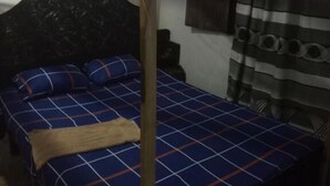 Quarto com cama, ventilador de teto e mosquiteiro.
