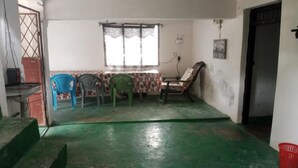 Um quarto com piso verde, uma mesa com cadeiras, uma janela e uma porta.