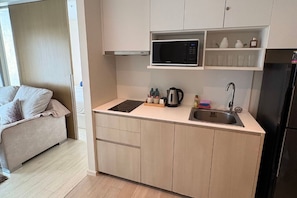 A compact kitchen with a microwave, sink, and cabinets. - Veranda one bedroom (Muang Pattaya)