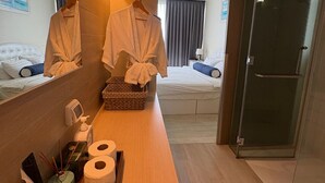 Ett hotellrum med två sängar, en träinredd hylla med toalettartiklar och en spegel som reflekterar rummet.
