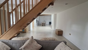 A modern interior with a wooden staircase leading to a kitchen area. - Bridge House Modern Comfort in Historic Stone (Scarborough)