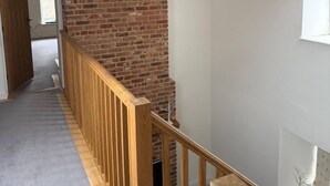 A staircase with a wooden railing, a brick wall, and hanging pendant lights. - Bridge House Modern Comfort in Historic Stone (Scarborough)